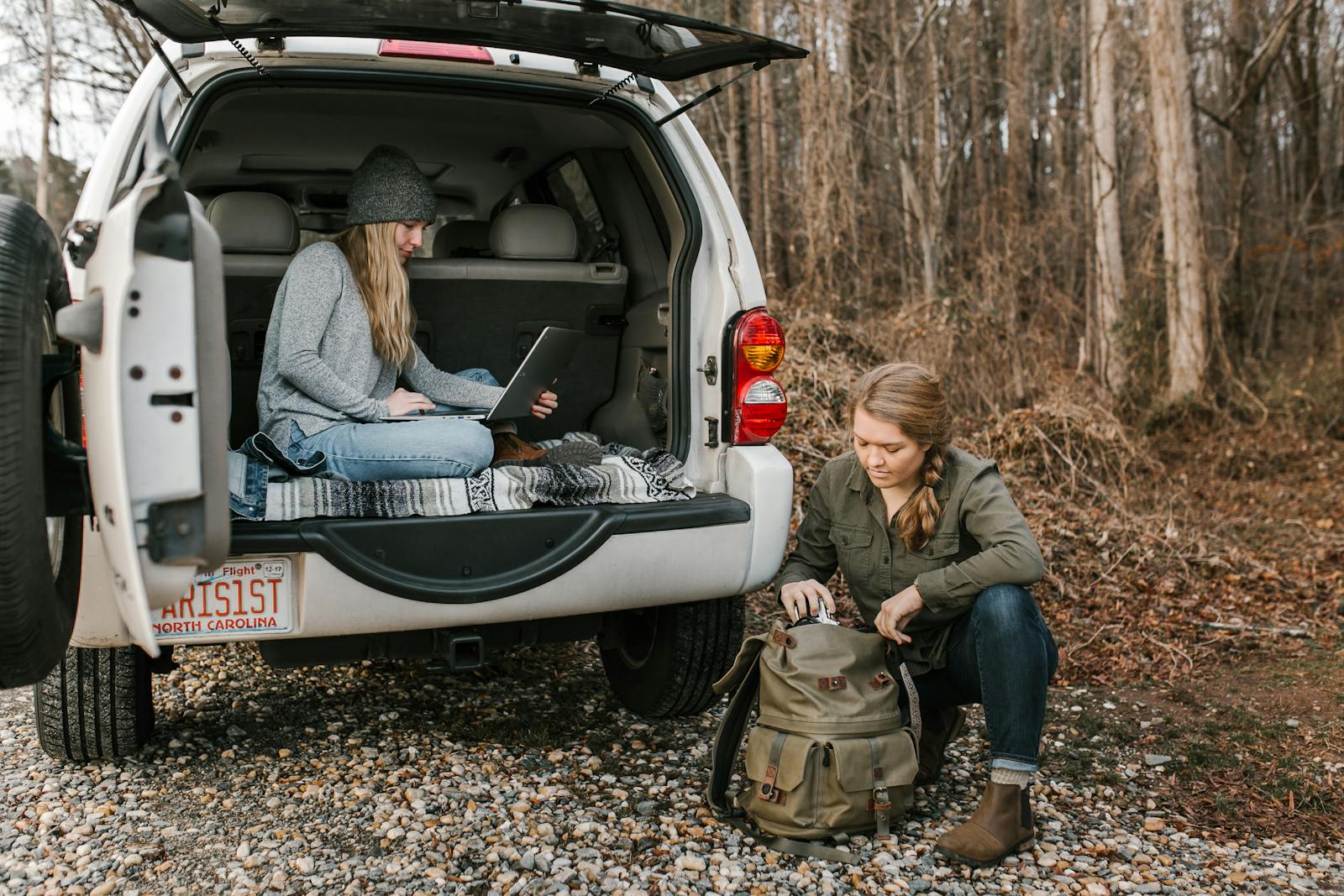 Two young women working remotely from a car in Greensboro's scenic outdoors.